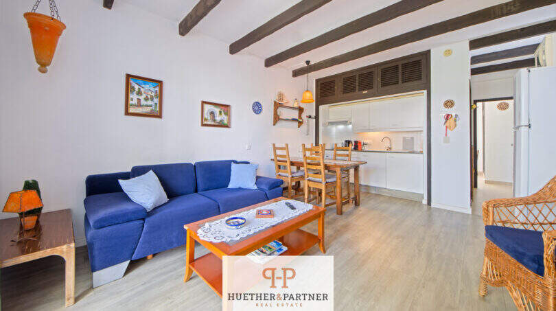 Wohnzimmer mit blauem Sofa, Holzbalkendecke und offener Küche in Terrassen-Wohnung, Cala d'Or