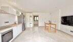 Cocina luminosa del apartamento de huéspedes en villa Marratxí con electrodomésticos modernos empotrados, mesa de comedor y suelo de baldosas de mármol.