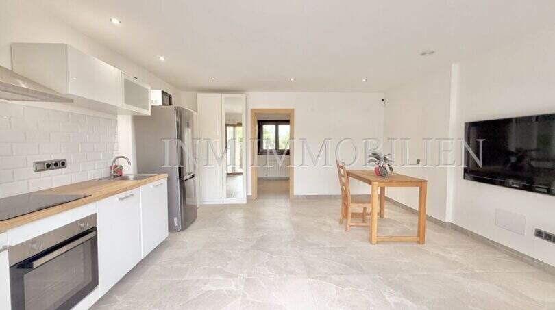 Cocina luminosa del apartamento de huéspedes en villa Marratxí con electrodomésticos modernos empotrados, mesa de comedor y suelo de baldosas de mármol.
