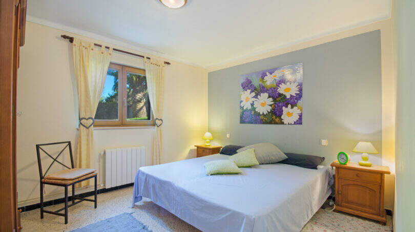 Helles Schlafzimmer der Finca Son Macià mit Doppelbett, Holzmöbeln und floralem Wandbild