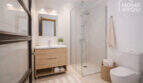 Modernes Bad im Herrenhaus Porreres: Glasdusche, Holzwaschtisch, WC und natürliche Dekoration in hellem Design.