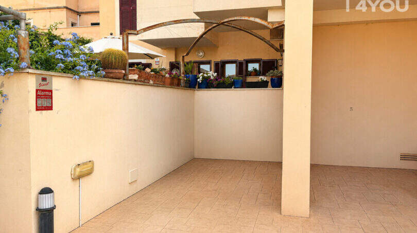 Überdachte Terrasse der 3-Zimmer-Wohnung in Llucmajor mit Fliesenboden und bepflanzter Außenmauer.