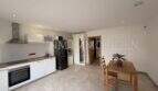 Cocina abierta con armarios empotrados blancos, placa de cocción, horno y zona de comedor en apartamento de huéspedes, villa Marratxí