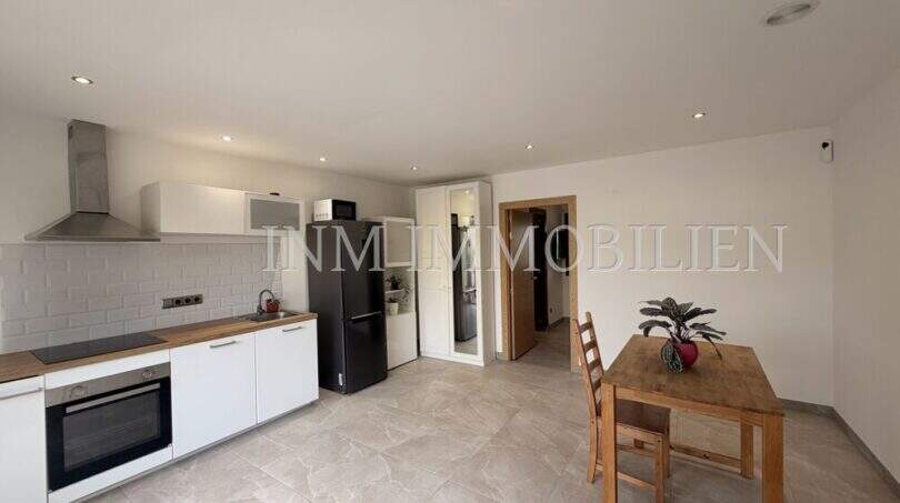 Cocina abierta con armarios empotrados blancos, placa de cocción, horno y zona de comedor en apartamento de huéspedes, villa Marratxí