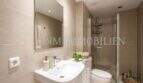 Cuarto de baño moderno del apartamento en primera línea de mar en Port Adriano con ducha, WC y decoración de azulejos beige claro.