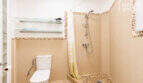 Badezimmer mit Dusche, WC, Kieselstein-Mosaik und Glasregalen in der Wohnung in Ses Salines