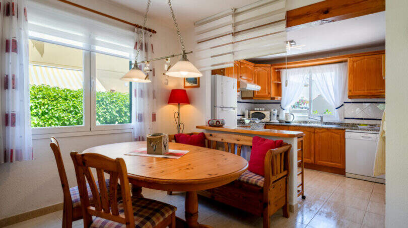 Helles Esszimmer mit Holztisch und Küche mit Holzfronten im Doppelhaus Cala Murada