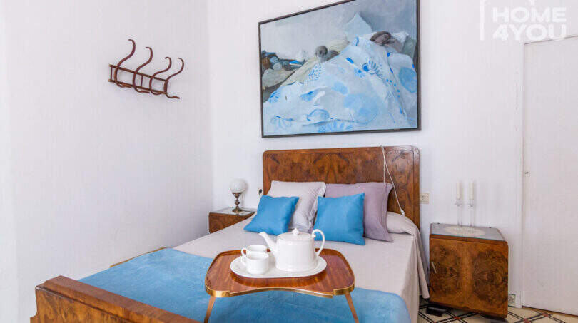 Schlafzimmer mit Doppelbett, Nussbaumholz-Möbeln, blauen Kissen und Gemälde im historischen Herrenhaus Porreres