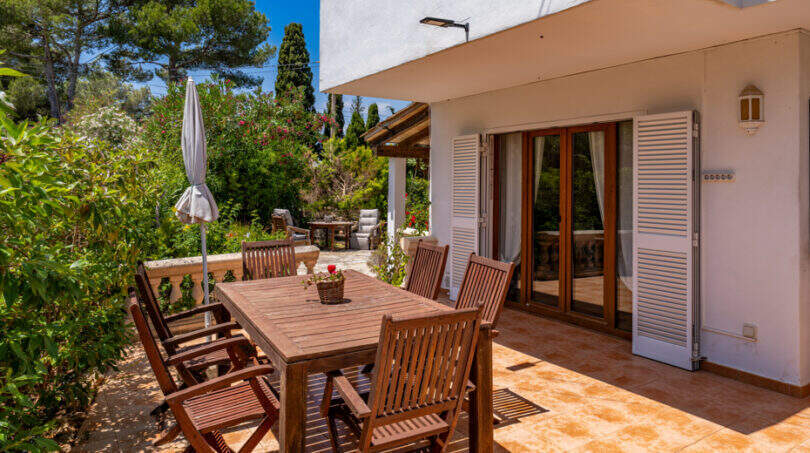 Sonnenterrasse mit Holzmöbeln und Gartenblick am Erdgeschossapartment in Cala Murada