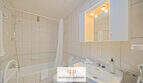 Helles Badezimmer mit Badewanne, Dusche, Waschbecken und beleuchtetem Spiegelschrank in Cala d'Or Appartement.