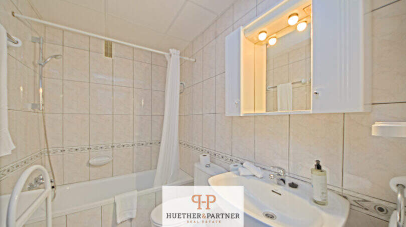 Helles Badezimmer mit Badewanne, Dusche, Waschbecken und beleuchtetem Spiegelschrank in Cala d'Or Appartement.