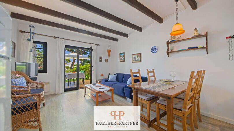 Helles Wohnzimmer mit Holzbalken, blauem Sofa, Esstisch und Terrassentür zum Garten in Cala d'Or.