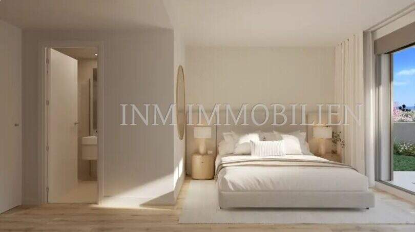 Bright bedroom of a new construction apartment in Palmanova with double bed, wooden floor and balcony access to the garden.