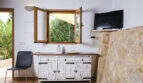 Wohnzimmer mit Holzbalkendecke, rustikalem Sideboard, Natursteinwand und Gartenblick durchs Fenster