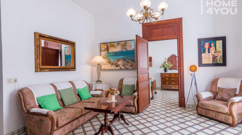 Wohnzimmer des historischen Herrenhauses in Porreres mit Originalfliesen, Kronleuchter, Gemälden und klassischen Sitzmöbeln.