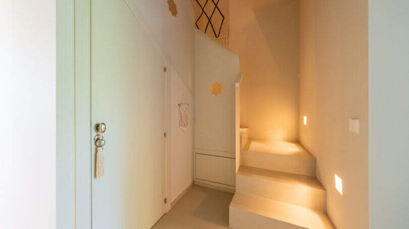 Heller Eingangsbereich mit Treppe, eingebetteten Stufenlichtern und mintfarbenen Einbauschränken in mallorquinischer Finca.