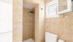 Badezimmer mit beigen Fliesen, Dusche, WC und Fenster in Erdgeschosswohnung nahe Strand Cala Llombards