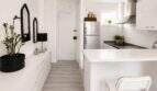 Heller, moderner Wohnbereich mit weißer Küchenzeile, Kochinsel und elegantem Flur im Penthouse Cala Major