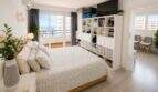 Helles Schlafzimmer im Meerblick-Penthouse Cala Major mit Doppelbett, Balkon und weißem Regal.