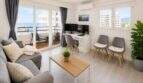 Helles Wohnzimmer mit grauer Couch, Balkon mit Meerblick und modernem Arbeitsbereich im Penthouse Cala Major