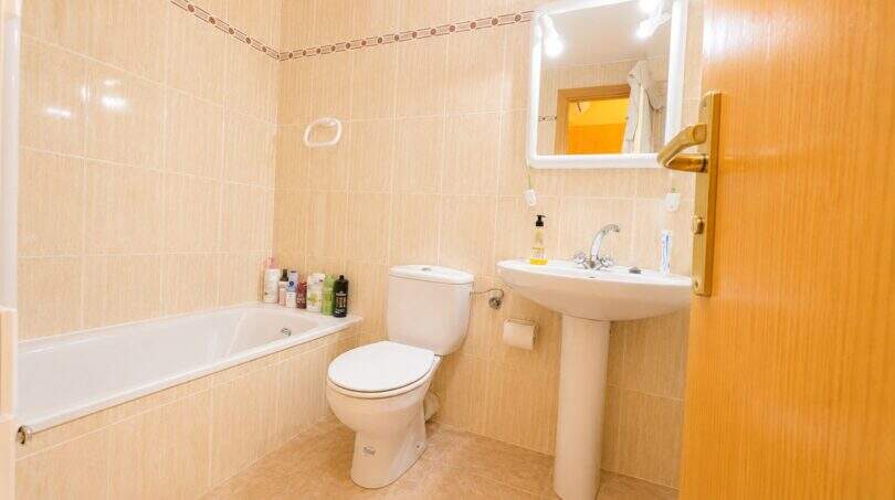 Helles Badezimmer der Maisonette in Llucmajor mit Badewanne, WC und Waschbecken, beige Fliesen.