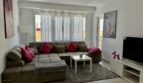 Helles Wohnzimmer mit großem Ecksofa, rosa Kissen, Flachbild-TV und Balkonzugang in Palma de Mallorca