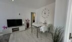 Helles Wohnzimmer mit TV-Möbel, Esstisch und Wanduhr in modernisierter Strandwohnung Palma de Mallorca