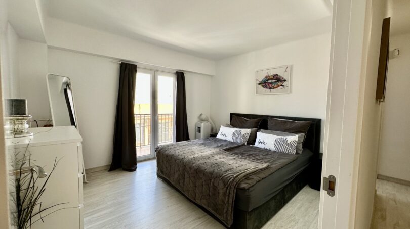 Modernes Schlafzimmer mit Doppelbett, dunklen Vorhängen und Balkonzugang in strandnaher Wohnung in Palma