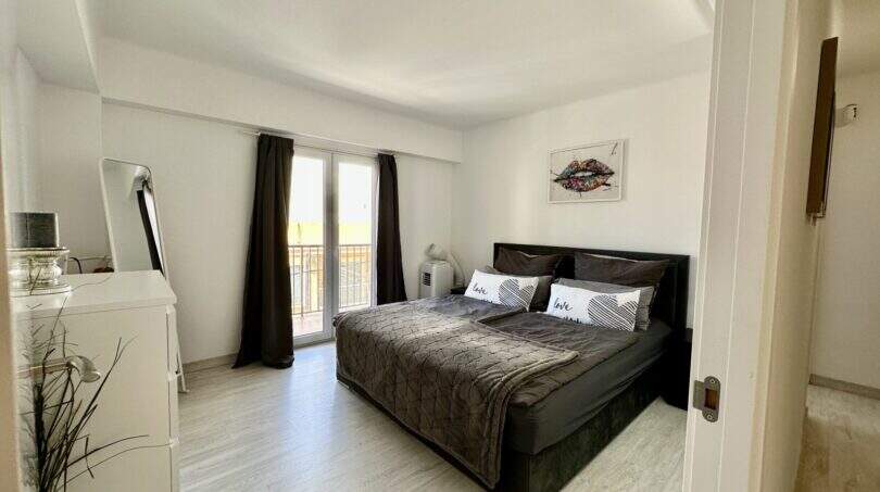 Helles Schlafzimmer mit Doppelbett, dunklen Vorhängen und Balkonzugang in strandnaher Wohnung Palma de Mallorca