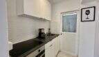 Moderne weiße Küche mit Induktionskochfeld, Kaffeemaschine, Spüle und Weinzeit-Wandbild in Strandwohnung Palma