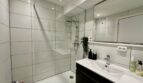 Modernes Badezimmer mit Regendusche, weißen Großformatfliesen, Waschtisch und Spiegel in Strandwohnung Palma