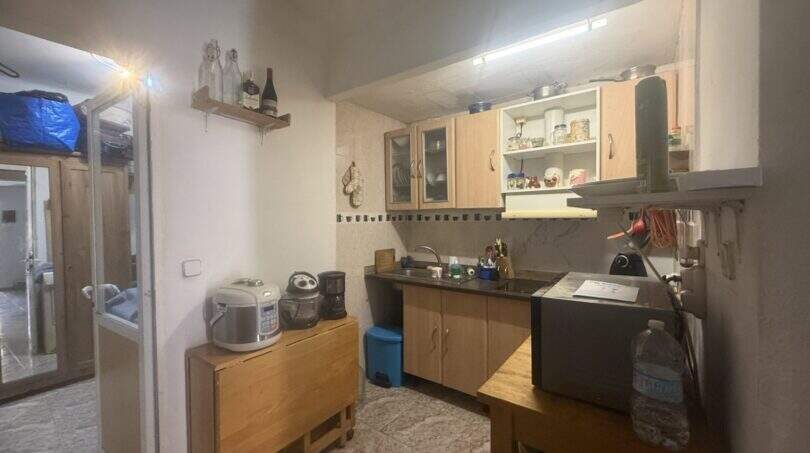Kleine gemütliche Küche mit Holzschränken, Küchengeräten und Ablageregalen in Wohnung in Inca