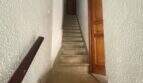 Schmales Treppenhaus mit Steinstufen, Holzhandlauf und Holztür in charmanter Wohnung in Inca.