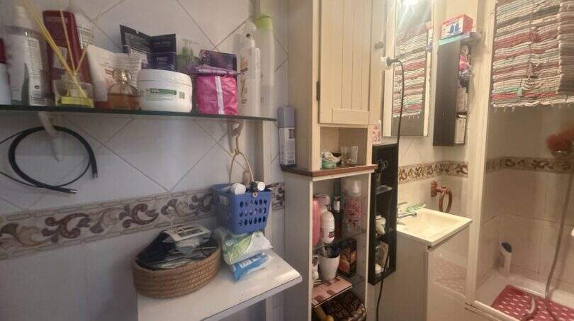 Kleines Badezimmer mit Waschbecken, Dusche, Wandregalen und Stauraum in charmanter Wohnung in Inca.