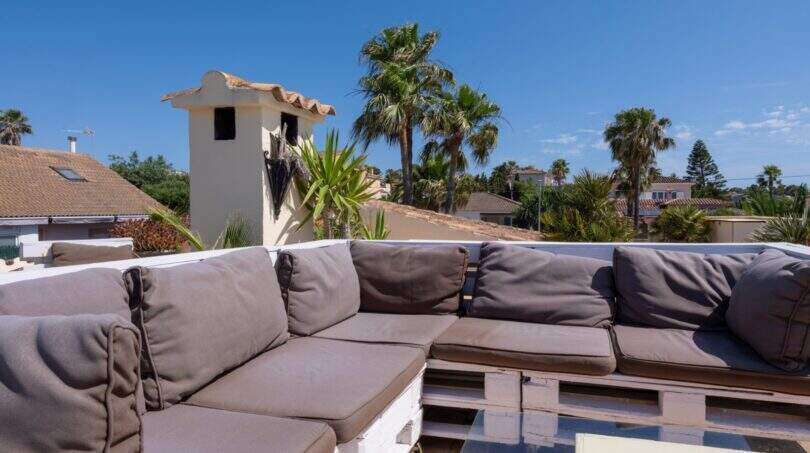 Dachterrasse mit grauer Lounge-Sofa-Gruppe aus Paletten, Meerblick und Palmen in Llucmajor