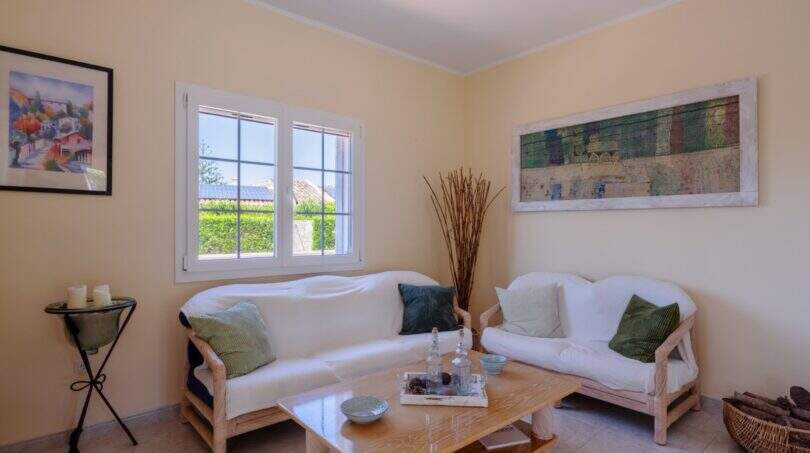 Helles Wohnzimmer mit weißen Rattansofas, Holztisch und mediterranem Flair im Bungalow Llucmajor