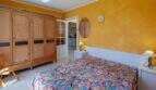 Schlafzimmer mit Doppelbett, gelbен Wänden und Holzschrank im mediterranen Bungalow in Llucmajor