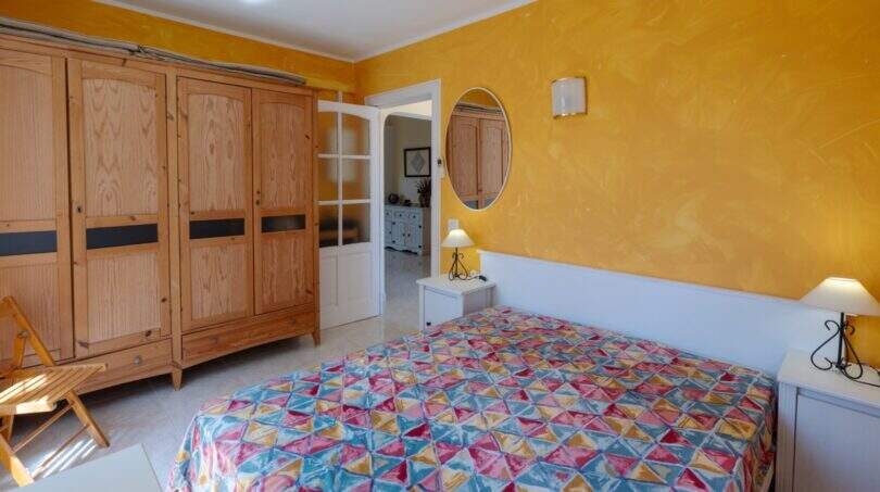 Schlafzimmer mit Doppelbett, gelbен Wänden und Holzschrank im mediterranen Bungalow in Llucmajor