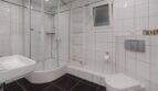 Helles Badezimmer mit Eckdusche, Wandtoilette, Heizkörper und weißen Fliesen im Bungalow Llucmajor
