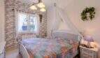 Schlafzimmer mit Himmelbett, Kelim-Tagesdecke, Backsteinwand & Baldachin in mediterranem Bungalow Llucmajor