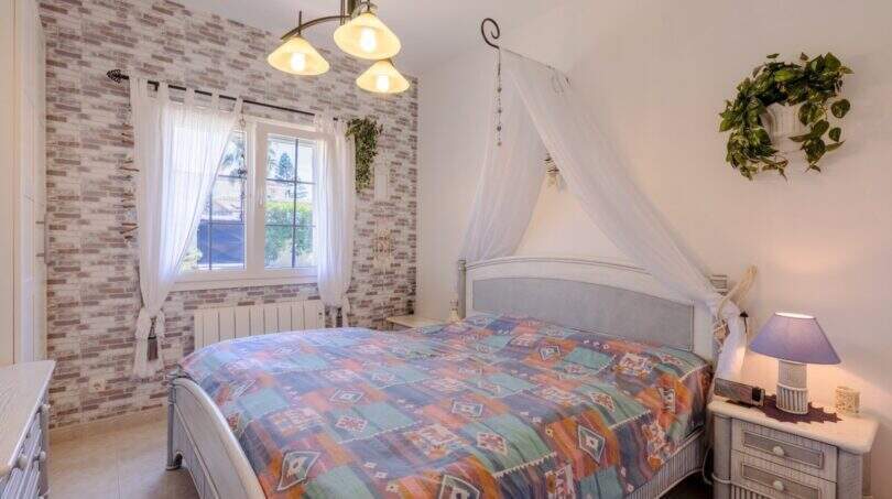 Schlafzimmer mit Himmelbett, Kelim-Tagesdecke, Backsteinwand & Baldachin in mediterranem Bungalow Llucmajor