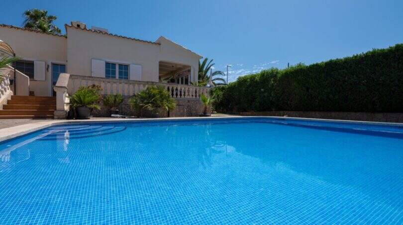 Großer blauer Pool vor mediterranem Bungalow mit Balustrade und Palmen in Llucmajor