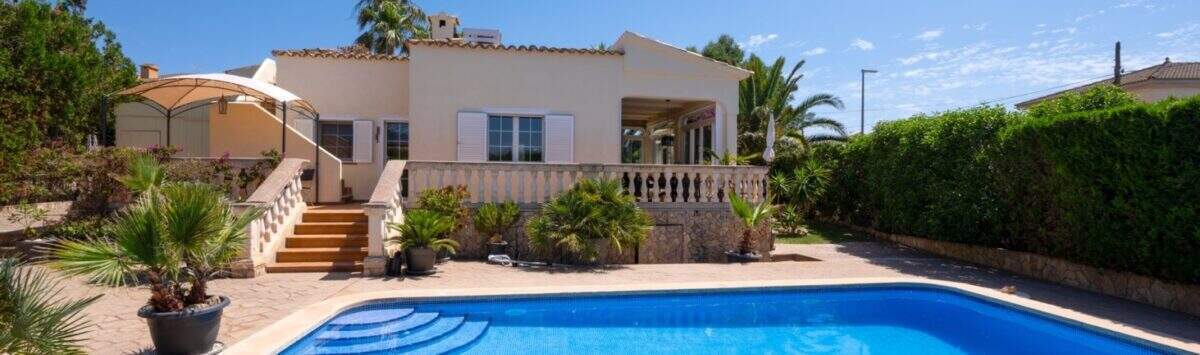 Bungalow mediterráneo en Llucmajor con gran piscina, terraza y palmeras bajo cielo azul.