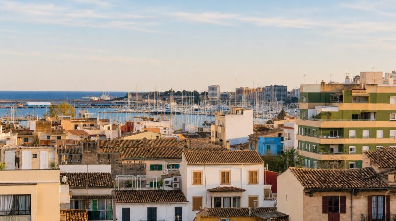Panoramablick über die Dächer von Palma de Mallorca mit Hafen und Mittelmeer im Hintergrund.