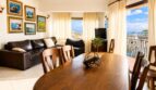 Helles Wohn-Esszimmer mit Holztisch, Ledersofa und Balkon mit Panoramablick über Palma de Mallorca