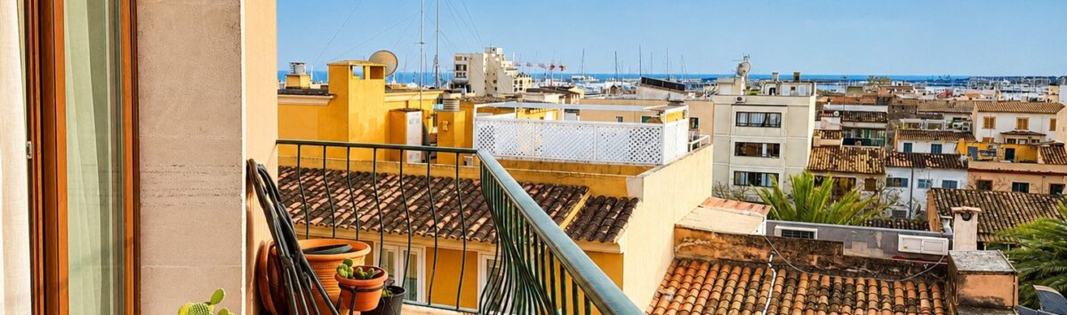 Balcón soleado con cactus, vistas sobre los tejados de Palma y el mar, arquitectura mediterránea
