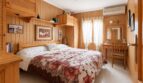 Gemütliches Schlafzimmer mit Holzvertäfelung, Doppelbett, Blumendecke und Klimaanlage im Penthouse Palma
