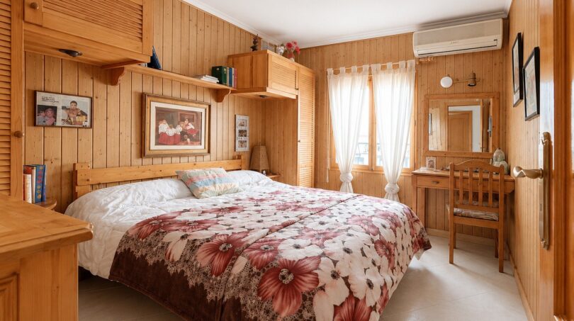 Gemütliches Schlafzimmer mit Holzvertäfelung, Doppelbett, Blumendecke und Klimaanlage im Penthouse Palma