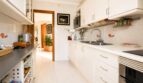Helle Einbauküche mit weißen Fronten, Granitarbeitsplatte und Fliesenboden im Penthouse Palma de Mallorca