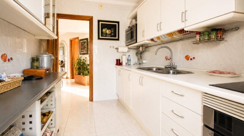 Helle Einbauküche mit weißen Fronten, Granitarbeitsplatte und Fliesenboden im Penthouse Palma de Mallorca